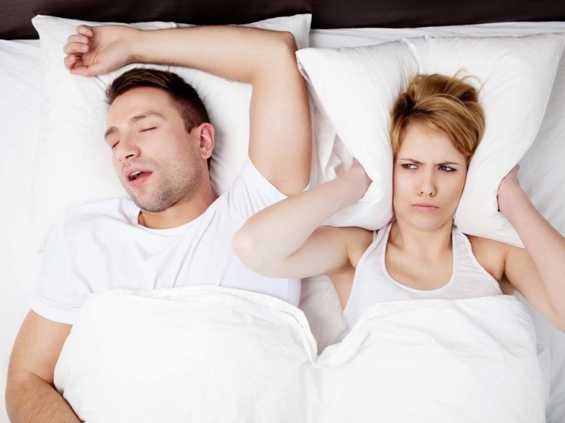 A man sleeping while snoring and woman covering her ears with pillow How Small Changes Can Improve Well-Being & Life Satisfaction